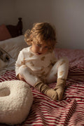 little boy sitting on bed next to boucle pillow by bettys home