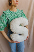 boucle letter cushion S Bettys home held by woman in green shirt on cream wall 