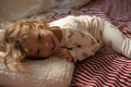 little boy lying on boucle cushion by bettys home on bed