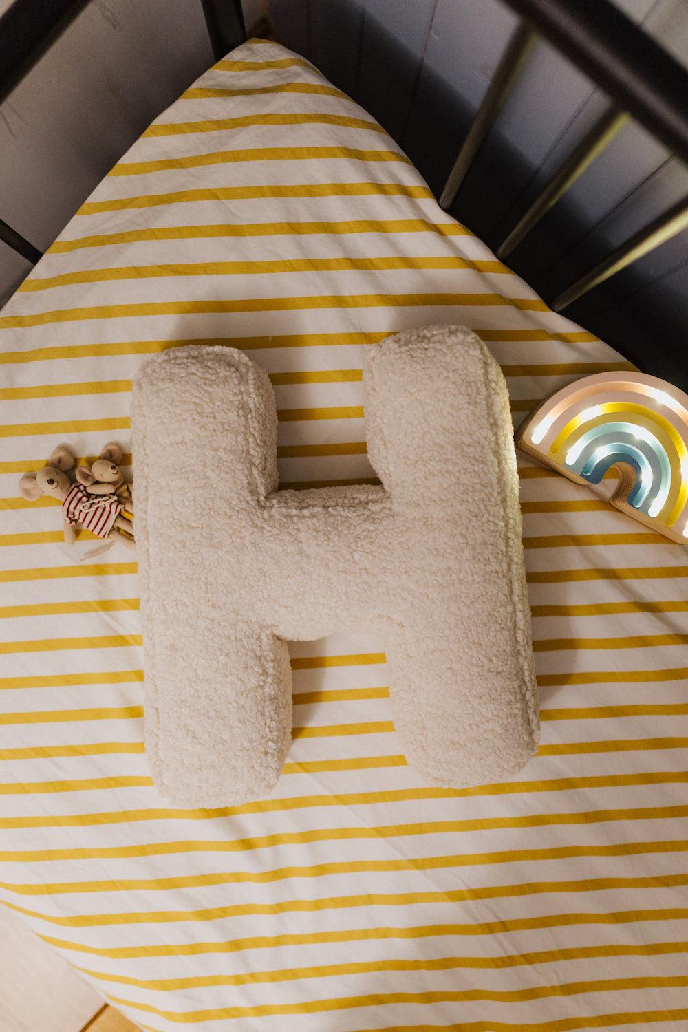 Boucle letter pillow H lying in kids crib next to maileg mouse as kids room deco